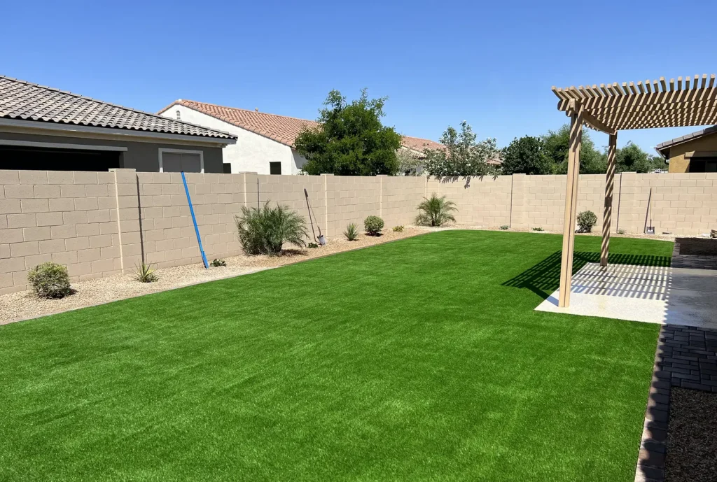 Finished artificial turf backyard with pergola and block wall at a Chandler AZ home