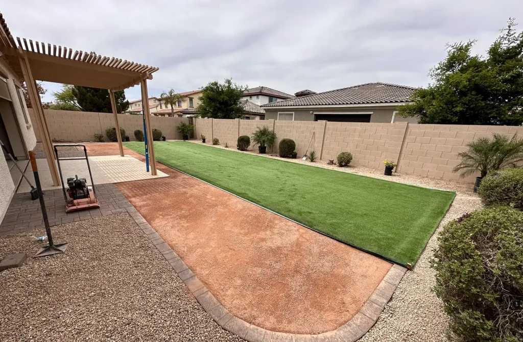 Colored concrete patio paired with an artificial turf lawn in a finished backyard