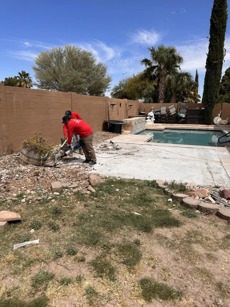 Crew breaking up old concrete near a backyard pool