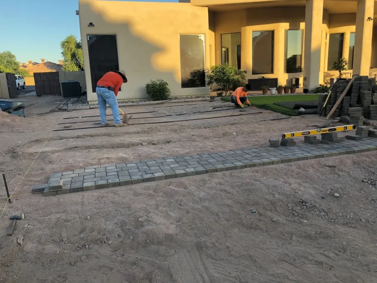 CGL crew setting a paver border on a graded base in front of a home