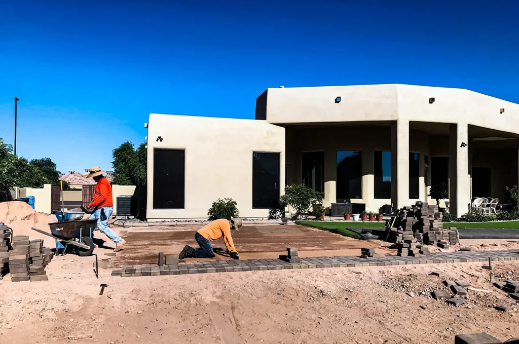 CGL crew laying pavers on a graded base in front of a southwest style home