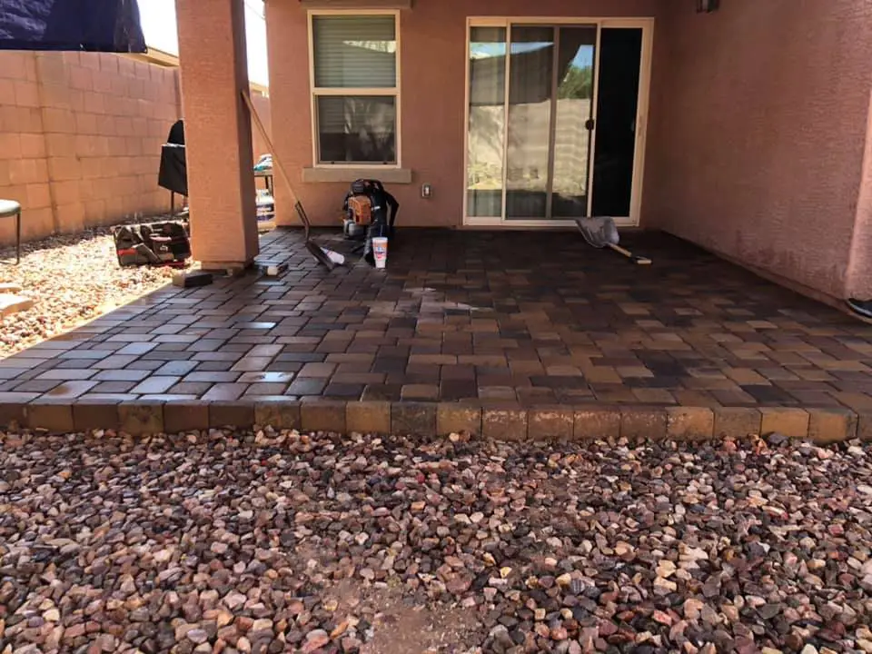 Newly installed paver patio behind a Chandler AZ home with decorative rock border