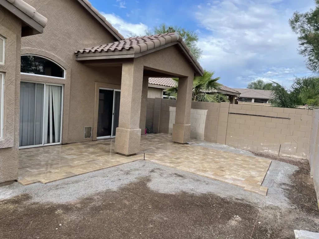 Travertine patio under a covered back porch, with the yard graded for landscaping