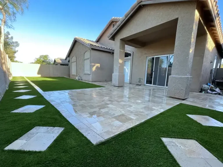 Travertine paver patio with artificial turf inlay strips in a finished backyard