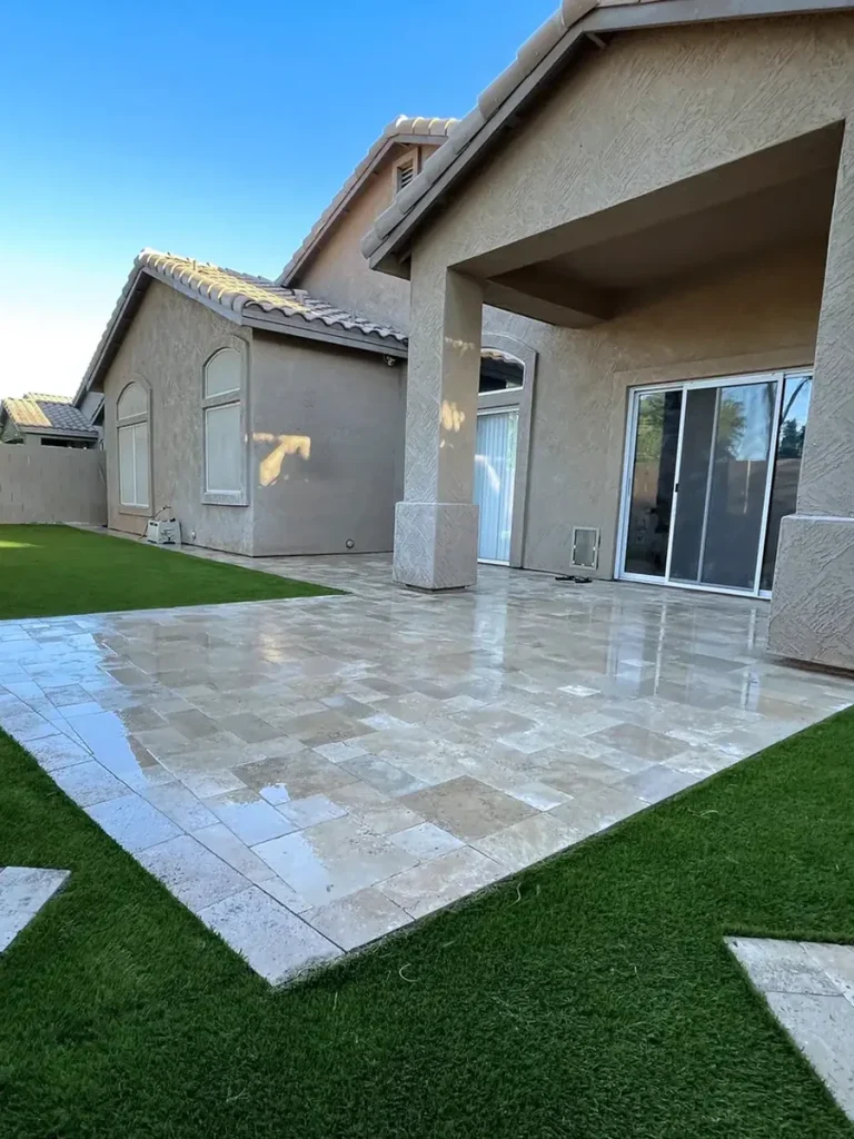 Travertine paver patio with artificial turf inlay strips in a finished backyard